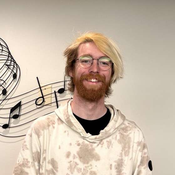 Michael Chipchak standing in front of a sheet music decal and wearing a hoodie.